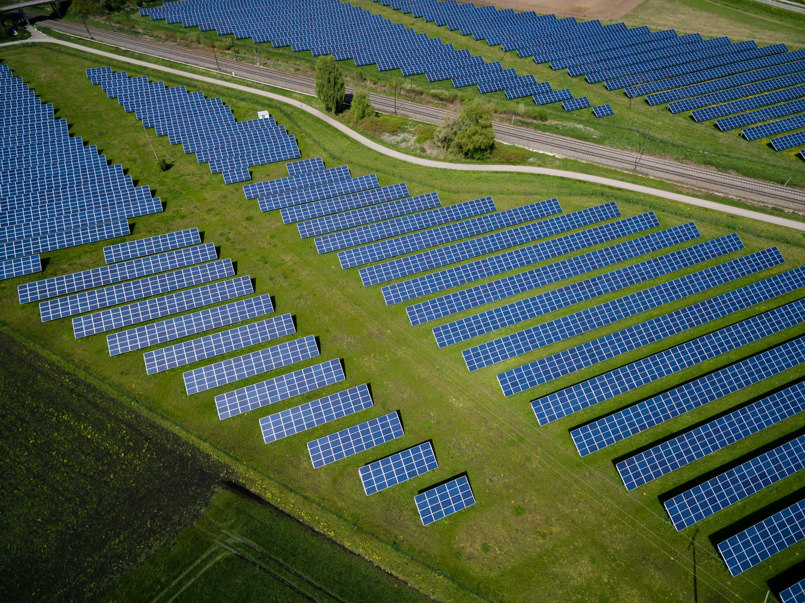 Aerial view of a large-scale photovoltaic solar plant surrounded by green fields