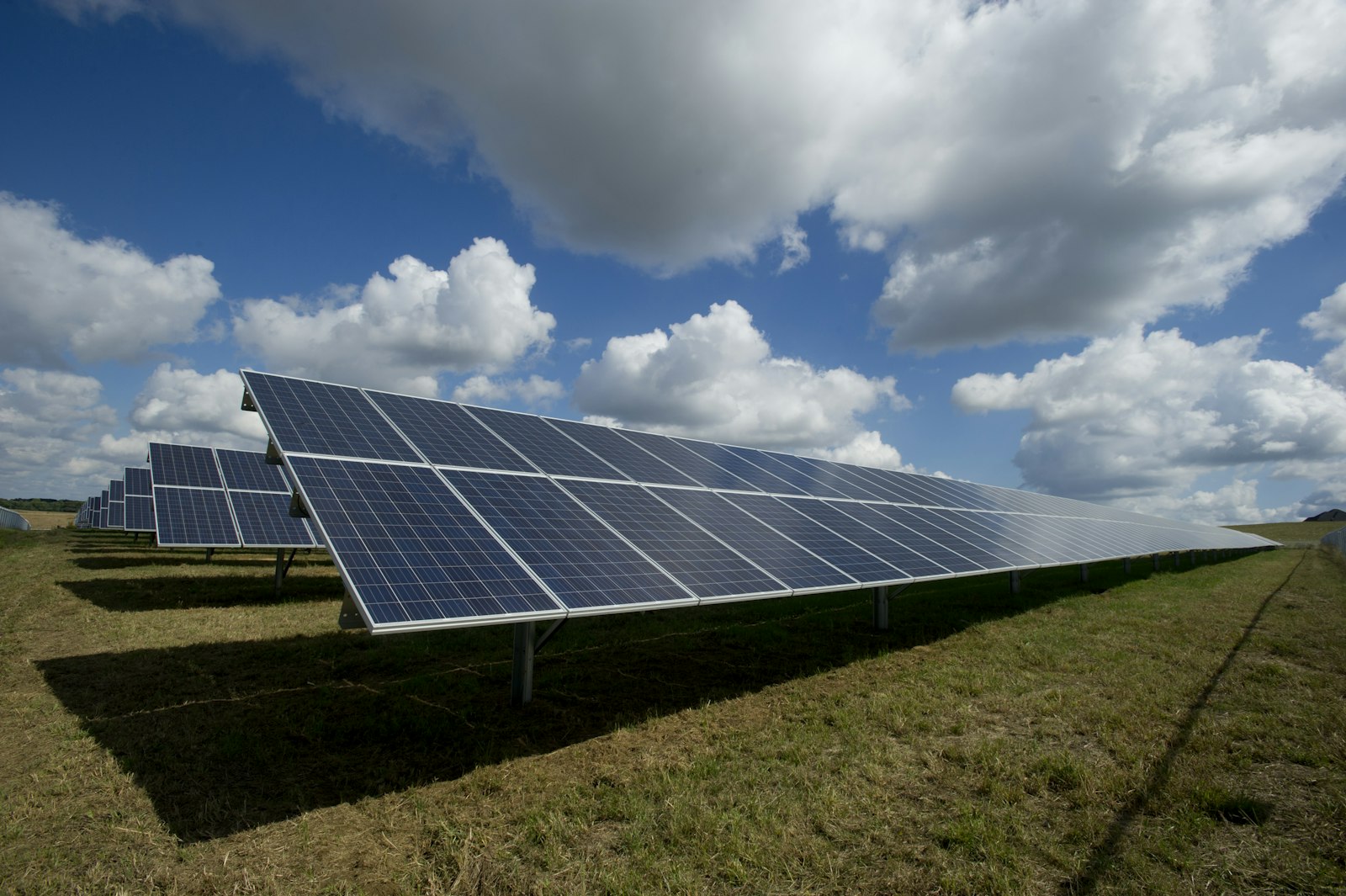 Solar panels facing the sun with mountains and a clear sky in the background